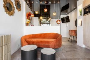 a living room with an orange couch and two stools at Le Daïquiri Renovated Apartment with Terrace in the Naturist Village in Cap d'Agde
