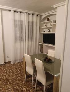 a dining room with a green table and white chairs at Casa Paco in Linares