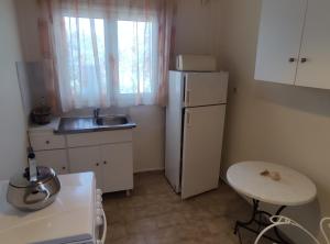 a small kitchen with a white refrigerator and a table at Blue and White Apartments 1 in Benitses