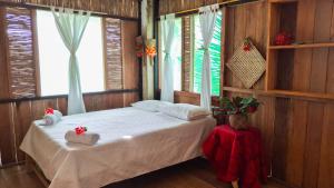 a bedroom with a bed in a room with windows at Posada Nore, Nuquí in Arusí