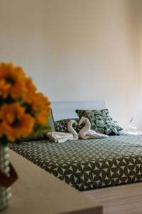 Zwei Schwäne sitzen auf einem Bett mit einer Vase voller Blumen in der Unterkunft Santa Sofia Suite in Lendinara