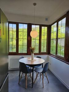 a dining room with a table and chairs and windows at Ponti House Dilijan - beautiful 2 bedroom house and separate 1 bed unit, sleeps 6 in Dilijan