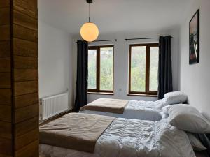 a bedroom with two beds and two windows at Ponti House Dilijan - beautiful 2 bedroom house and separate 1 bed unit, sleeps 6 in Dilijan