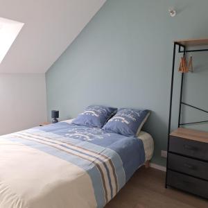 a bedroom with a bed with blue pillows and a dresser at Ma Petite Maison in Belz