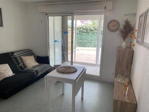 a living room with a couch and a table and a clock at T1 Familial avec Terrasse, Piscine, Plage à 6 Min à Pied et Aqualand à 2 Min in Cap d'Agde