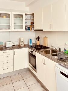 a white kitchen with white cabinets and a sink at Vista Dourada in Porto Santo