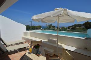 a white umbrella sitting on a balcony next to a swimming pool at Kathara Bay Apartments in Faliraki