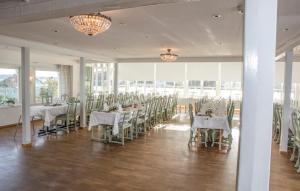 una sala banchetti con tavoli e sedie bianchi e finestre di Rågårdsvik a Grundsund