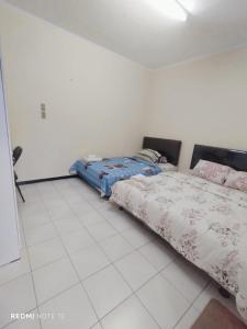 two beds in a room with a white tiled floor at Kos di Menteng, Jakarta Pusat in Jakarta