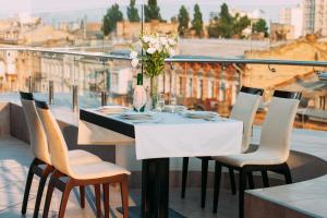 a table with chairs and a vase of flowers on a balcony at Alarus Luxe Hotel in Odesa