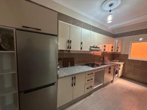 a kitchen with white cabinets and a stainless steel refrigerator at Appartement à Houma, proche Port Tanger Med in Dalia