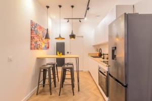 a kitchen with a bar with stools and a refrigerator at Le Quatrième Mur in Saint-Quentin