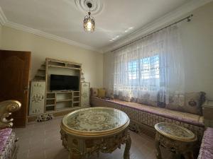 a living room with a table and a tv and a window at Appartement à Houma, proche Port Tanger Med in Dalia