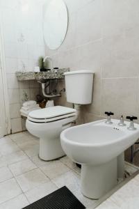 a white bathroom with a toilet and a sink at Los Geranios Apart in Villa Cubas +10 photos