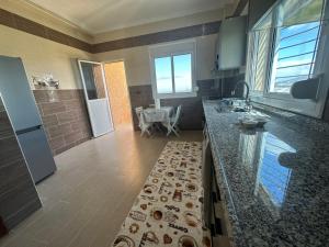 a kitchen with a long counter with a counter top at Appartement à Houma, proche Port Tanger Med in Dalia
