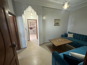 a living room with a blue couch and a table at Appartement à Houma, proche Port Tanger Med in Dalia
