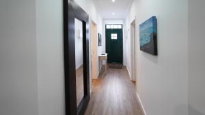 a hallway with white walls and wooden floors and a painting at Casa do Negrão in Ponta Delgada