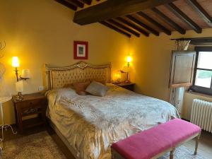 a bedroom with a large bed with a pink seat at Villa Bellora in Cortona