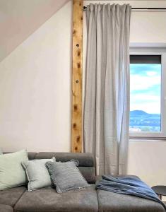 ein Wohnzimmer mit einer Couch und einem Fenster in der Unterkunft Egy présház tágas tetőtere mesés kilátással in Hegymagas
