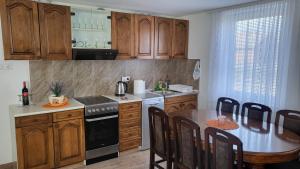 a kitchen with wooden cabinets and a table with a dining room at Apartman Villa Ruža in Golubac