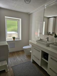 a bathroom with two sinks and a toilet and a window at Ubytovanie Hronec in Hronec +18 photos