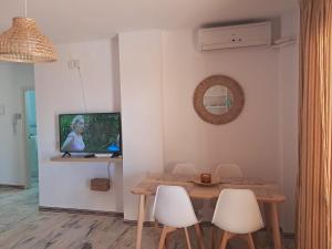 a dining room with a table and a tv on a wall at La caracola in Novo Sancti Petri