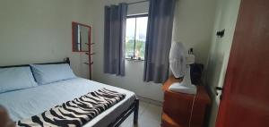 a bedroom with a bed and a fan and a window at quarto duplo in Caraguatatuba