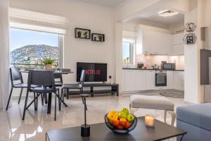 a living room with a kitchen and a table with a bowl of fruit at Era Suites Lagonisi in Kalívia Thorikoú