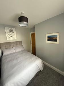 a bedroom with a white bed and a picture on the wall at The Clara, Ballycastle in Ballycastle