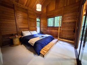a bedroom with a bed in a room with wooden walls at Cabana de madeira entre as árvores in Piedade