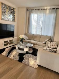 a living room with a couch and a tv at Bedroom with private bathroom in Southwest in Edmonton