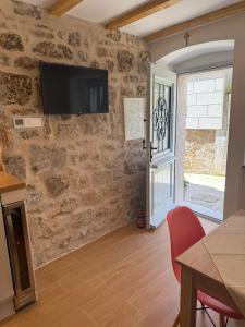 a living room with a tv on a stone wall at Little House Komiza in Komiža