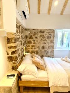 a bed in a room with a stone wall at Little House Komiza in Komiža
