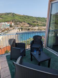 Un balcón con dos sillas y una mesa con una copa de vino. en T2 Vue mer à 15 min de Collioure, en Banyuls-sur-Mer