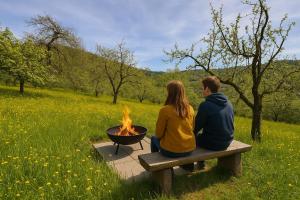 a couple sitting on a bench near a fire pit at Romantik pur - Schlafen unter dem Sternenhimmel in Ebersberg
