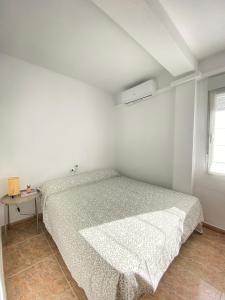 ein weißes Schlafzimmer mit einem Bett und einem Tisch in der Unterkunft Balears Relax Apartment in Puerto de Gandía