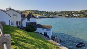 a house on a hill next to a body of water at The Old Post Office in Coverack