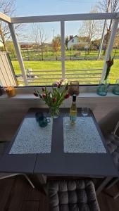 a table in front of a window with a bottle and flowers at Dębowy Zakątek in Zarzecze +14 photos