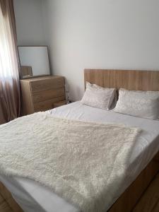 a bedroom with a white bed with a wooden headboard at Appartement de standing à EZZAHRA in Ez Zahra