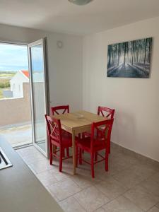 a dining room with a table and four red chairs at Vila Kula in Nin