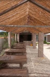 a pavilion with wooden benches on a stone patio at Vila Kula in Nin