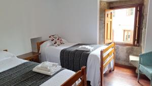 Un dormitorio pequeño con dos camas y una ventana. en San Roque 52, en Combarro