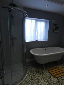 a bathroom with a tub and a shower with a window at White Swan Inn in Belford