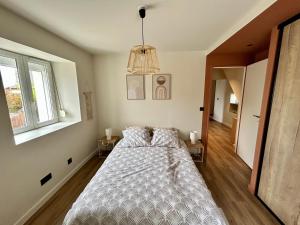 a bedroom with a bed and a chandelier at La Ferme de Gabriela, logement haut de gamme dans le Jura in Châtillon