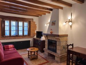 a living room with a fireplace and a red couch at Apartamentos Villa Julieta in Ruente