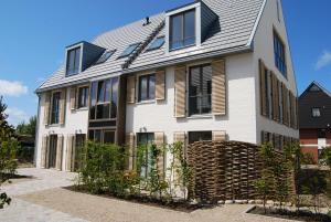 a white house with black windows and a roof at Luxuswohnung Abendsonne in Wenningstedt
