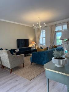 een woonkamer met een blauwe bank en een tv bij Franschoek Lermitage Villa 33 Three Bedroom Lake View in Franschhoek
