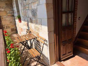 a wooden bench sitting next to a building with a door at Apartamentos Villa Julieta in Ruente