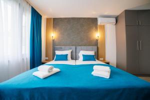 a large blue bed with two white towels on it at Aman Apartments in Sarajevo
