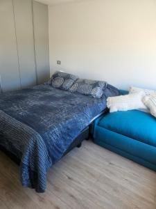 a bedroom with a blue bed and a couch at Steps to the beach, comfortable in Caldera